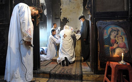 Coptic Christian priests praying for those killed by Islamic radicals in burned out Church in Egypt